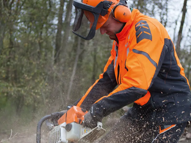 Ein Mitarbeiter von Göschlholz bei der konzentrierten Arbeit mit einer Motorsäge und fliegenden Holzspänen.